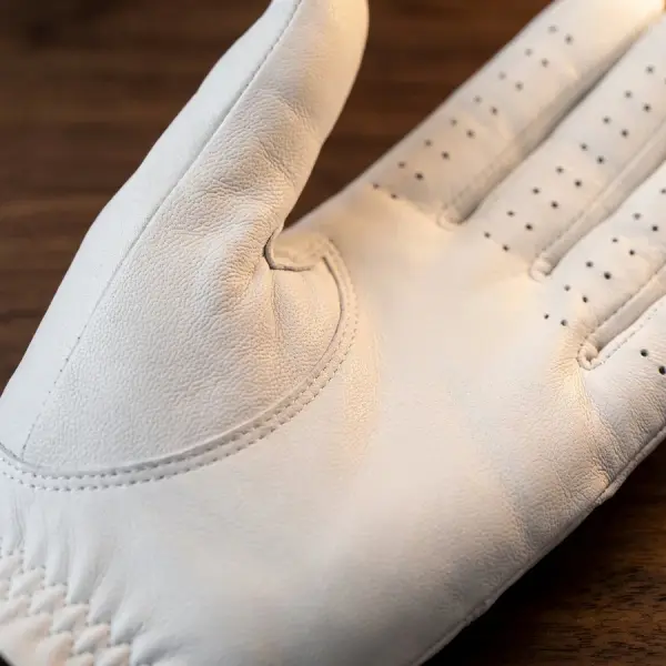 Palm of the white cabretta glove resting on a walnut table